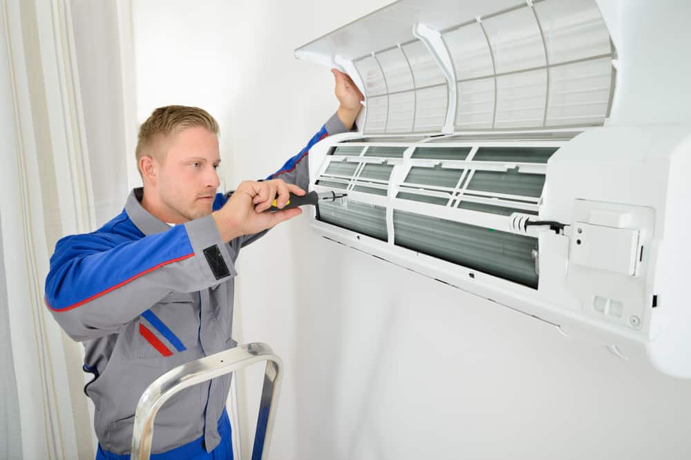 hvac technician working on wall mounted interior ac unit.